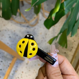 Handmade ladybug hair clip in yellow and black with rhinestones on a steady duckbill base