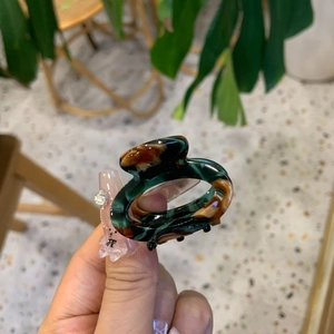 Mini acetate hair claw clip with dark green tortoiseshell texture and glossy finish