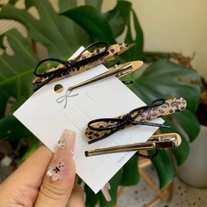 Leopard print bow hair clip set with simple metal duckbill clips on display card