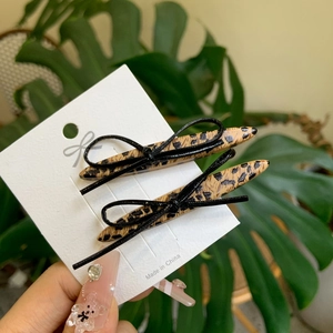 Sweet leopard print bow hair clips set on display card with green leaf background