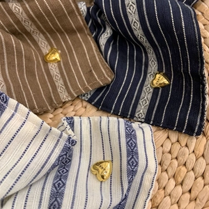 Detail of striped fabric hair scrunchies with heart metal charms on woven mat