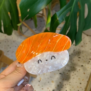 Pince à cheveux sushi au saumon avec visage de boule de riz et texture orange vive