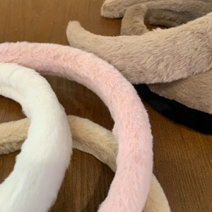 Macro detail of thick faux fur headbands in various colors on wooden surface