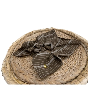 Brown striped scrunchie with a gold heart charm on a rustic woven background