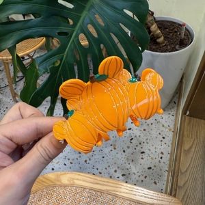 Vue détaillée d'une pince à cheveux citrouille orange en matériau acrylique brillant