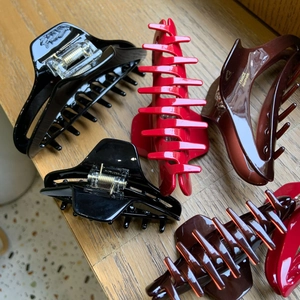 Close-up of elegant glossy hair clips in red, black, and brown with gold spring detail