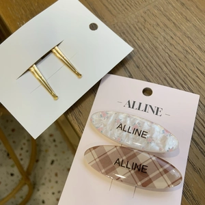 Close-up of floral and plaid oval hair clips with gold barrettes on display cards