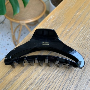 Elegant glossy black large hair claw clip with gold handmade lettering on wood background