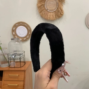 Close-up of a wide black plush headband with a thick, fluffy texture for daily styling