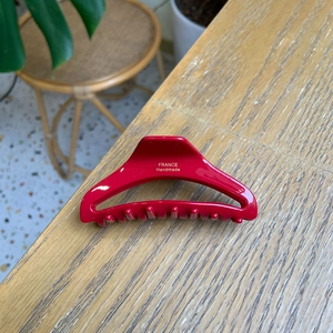 Close-up of bright red hair claw with gold France Handmade logo on light wood table