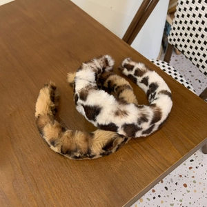 Gros plan de serre-têtes en peluche douce avec motifs léopard et vache sur bois