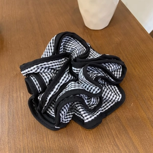 Classic black and white checkered scrunchie hair accessory on a rustic wooden background