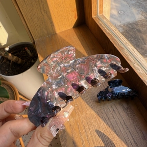 Gros plan sur une grande pince à cheveux en acétate avec texture marbrée violette