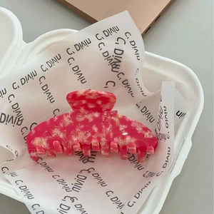 Détail macro d'une grande pince à cheveux en acétate avec motif marbré rose et ressort