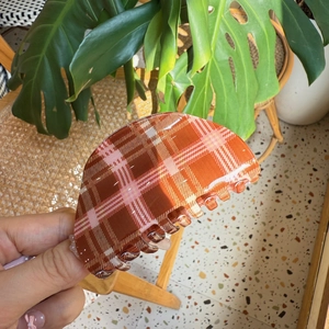 Close-up of a pink and brown plaid claw clip with a glossy finish and smooth teeth