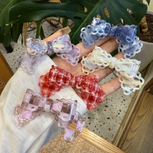 Close-up of five colorful lace-edged acetate bow hair clips in assorted patterns