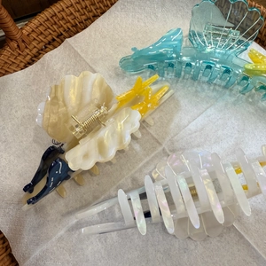 Détail de pinces à cheveux en acétate en forme de coquillage au fini nacré irisé