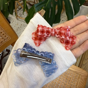Detail of red checkered and blue marble acetate bow hair clips with lace edges