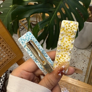 Detail of Y2K pearl hair clips with blue marble texture and yellow honeycomb design