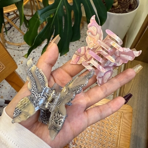 Detailed macro view of acrylic butterfly hair claw clip with marble texture finish