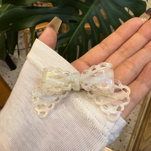 Lace-edged bow hair clip in iridescent pearlescent acetate with elegant wavy cutout design