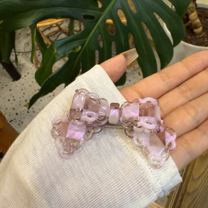 Pink marble acetate bow hair clip with lace cutout edges and elegant pearlescent finish