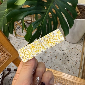 Y2K honeycombed yellow resin hair clip with pearl accents in a hand-held display shot