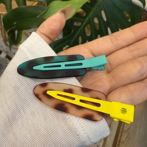 Gros plan de barrettes à cheveux léopard élégantes en bleu et jaune sur une main