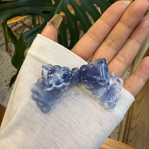 Detail of blue and purple marble acetate bow hair clip with hollow lace edges