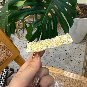 Detail of yellow honeycomb pearl hair clip with resin texture for women fashion