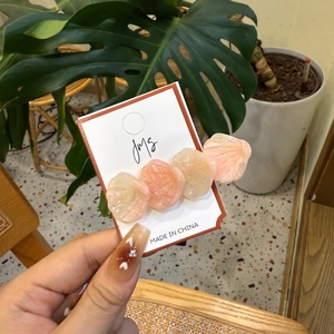 Pince à cheveux en forme de coquille en acétate rose et beige vue tenue dans la main
