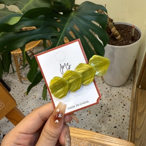 Vue détaillée de pinces à cheveux vertes en forme de coquillage sur une carte de produit