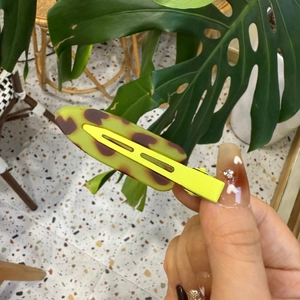 Gros plan sur une pince à cheveux léopard vert gelée avec des motifs de cœur bruns