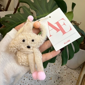 Detalle de un llavero de peluche de perro teddy con gorro y bufanda de punto rosa