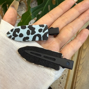 Détail de pinces à cheveux léopard montrant le tissu avant et le clip métallique noir