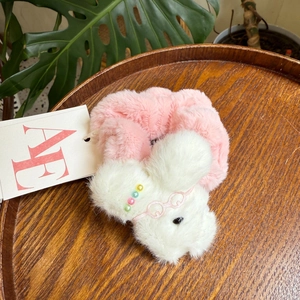 Detail eines rosa Plüsch-Haargummis mit süßem weißen Hund, Brille und bunten Perlen