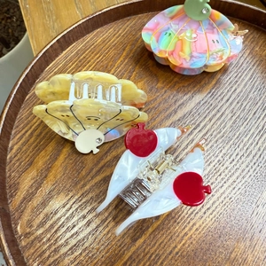 Detailed macro view of colorful acetate hair claws and butterfly clips on a wooden tray