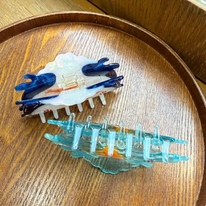 Blue whale and cloud shaped acetate hair clips displayed on a wooden tray