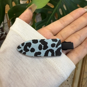 Détail d'une pince à cheveux motif léopard bleu clair avec attache en métal noir