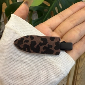 Détail d'une pince à cheveux en tissu à motif léopard avec une base en métal noir mat
