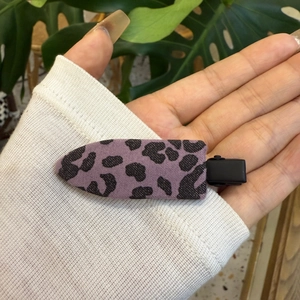 Détail d'une pince à cheveux violette à motif léopard avec enveloppe en tissu texturé