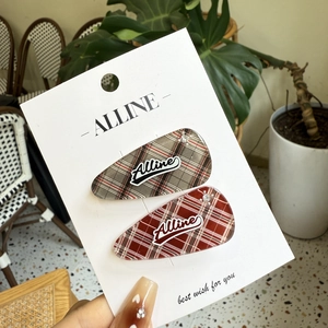 Detail view of red and green plaid hair clips with rhinestone accents and logo on card