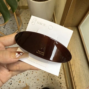 Macro shot of large oval tortoiseshell acetate hair clip with gold lettering