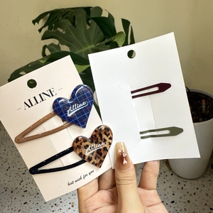 Detail of leopard print and blue plaid heart hair clips with brand tags