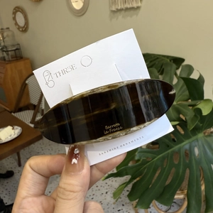 Detail of an oval tortoiseshell acetate hair barrette on a white branded display card