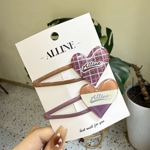 Set of two minimalist heart-shaped hair clips with plaid and patchwork designs on a white card