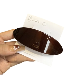 Elegant oval dark brown acetate hair barrette with gold lettering on display card