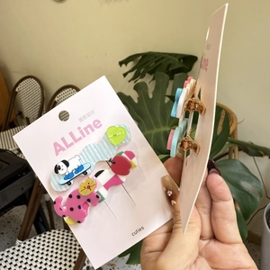 Dettaglio di fermagli per capelli in acrilico con gatto e cane su carta rosa con clip dorate