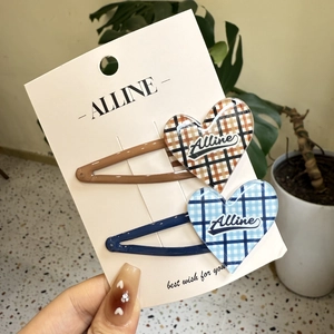 Close-up of heart-shaped plaid hair clips in brown and blue resin on display card