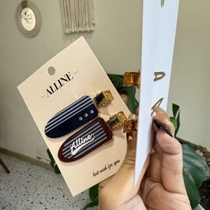 Detail of navy and burgundy textured hair clips with rhinestones on a display card